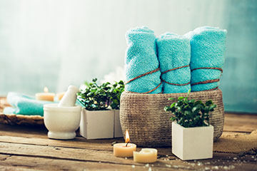 Spa accessories on rustic table, towels, candles, plants