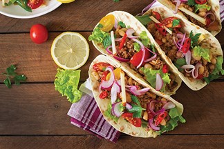 Authentic tacos with fresh fruit and vegetables on hard wood rustic table.