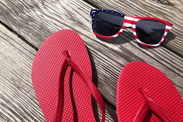 Red Flip-flops and sunglasses with an American flag theme rest on the Boardwalk in Atlantic City, NJ.