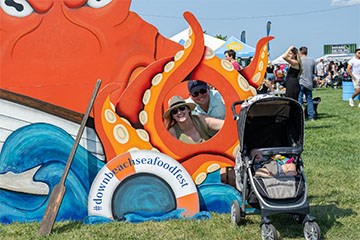 Downbeach Seafood Festival attendees using the backdrop sculpture of an octopus for a photo opportunity.