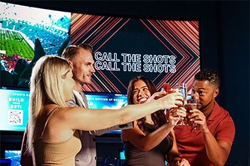 Call the Shots - two women and two men raise glasses at the Gallery Sportsbook and Bar at Ocean Casino Resort