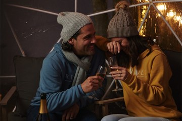 Couple smiling dressed warmly enjoy wine in Renault Winery Igloo.