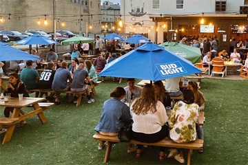 Tennessee Avenue Beer Hall Outdoor Space with people seated at picnic tables with Umbrellas.