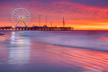 Steel Pier The Wheel reflecting off the beach and shoreline in Atlantic City at sunrise.