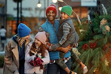 Family of four dressed warmly laughing while shopping during holidays.