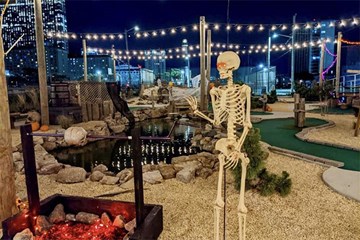 A skeleton with red lit up eyes stands nearby one of the many putting greens holes the mini-golf-course and well-lit mini-golf-course in the inlet section of Atlantic City.