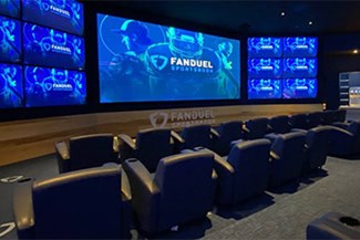 Plush seating and large screen tv in view. FanDuel Sportsbook logo on blue screen at Bally's Atlantic City.