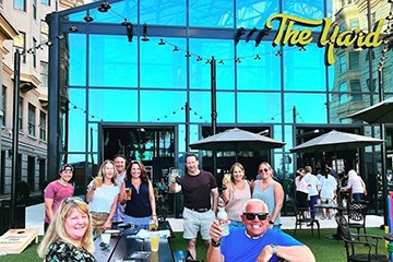 People raising glasses of beer outdoors at The Yard at Bally's casino Resort