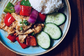 Chicken dish with fresh vegetables like sliced cucumbers and red peppers.